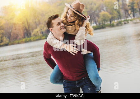 Playful couple. Portrait of handsome man giving piggy back ride à sa petite amie. Jeune homme portant belle femme sur les épaules. Couple having fun Banque D'Images