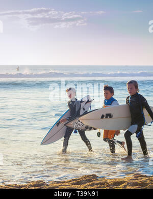 PENICHE, PORTUGAL - 20 octobre 2018 : trois garçons en combinaison avec des planches à la côte de l'océan, Peniche, Portugal Banque D'Images