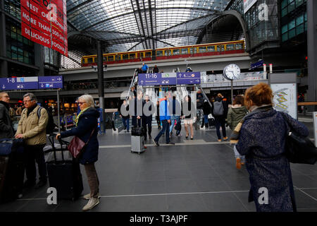 Navetteurs, voyageurs, touristes dans le centre commercial Berlin Hauptbahnhof avec un train S Bahn passant par les aériens, Berlin, Allemagne Banque D'Images