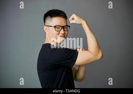 Jeune homme montrant biceps Banque D'Images