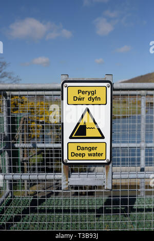 Anglais et Gallois multilingue de l'eau profond danger sign on clôture en acier galvanisé dans le nord du Pays de Galles UK Banque D'Images