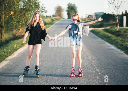 Young smiling happy girls having fun rollers ensemble sur la journée d'été Banque D'Images