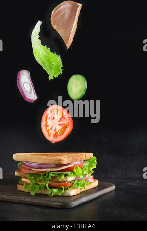 Voler des légumes pour sandwich, bacon, tomate, oignon, salade sur fond noir. Isolé Banque D'Images