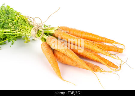 Ensemble beaucoup de domestiques de carotte orange avec des greens liées par le jute isolé sur fond blanc Banque D'Images