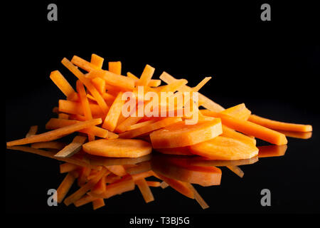 Groupe de cinq tranches beaucoup de morceaux de carotte orange de fines nouilles et rondelles isolé sur verre noir Banque D'Images