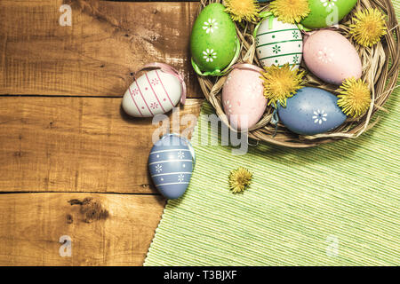 Les oeufs de Pâques colorés sur fond de bois avec fleurs de printemps, vue supérieure avec copie espace. Tons vintage photo. Banque D'Images