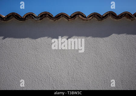 Sur le mur de plâtre blanc, l'arrière-plan ou de texture, le printemps de l'Europe, région de Pazardjik, Bulgarie. Haut de la paroi recouverte de deux couches de toit en céramique til Banque D'Images