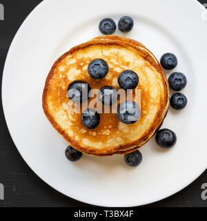 Crêpes maison avec des bleuets sur une plaque ronde blanche sur la surface noire, vue du dessus. Close-up. Mise à plat, les frais généraux, d'en haut. Banque D'Images