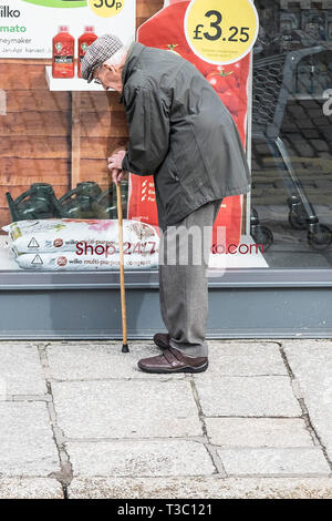 Un vieux monsieur se pencha sur son bâton de marche comme il regarde dans une vitrine. Banque D'Images