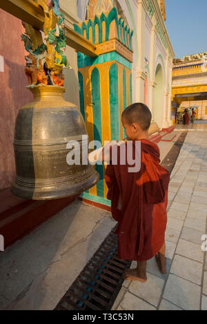 Moine Bouddhiste Novice frappant une cloche à la pleine lune du Vesak festival pour célébrer l'anniversaire de Bouddha à la pagode Shwe Yin Maw, près de Thazi, Myan Banque D'Images