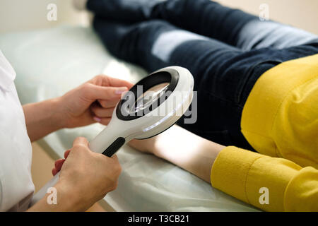 Dermatologue à l'aide d'une loupe professionnelle tout en faisant l'examen de la peau, contrôle sur la main. Les taupes bénigne Dermatologist examining birthmarks un Banque D'Images