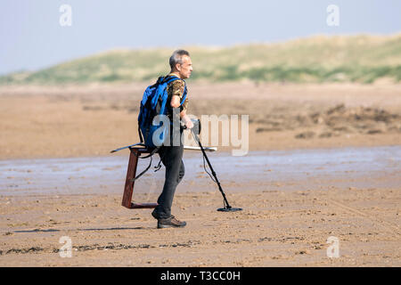 Un metal detectorist portant un marqueur de grille & détecteur de chasse pour de trésor caché sur le sable de la plage de Southport Merseyside. Banque D'Images