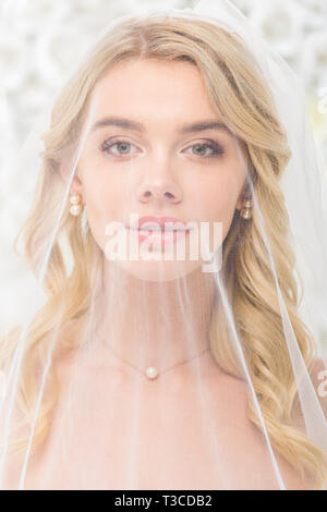 Portrait of attractive young woman with face recouverte de voile transparent sur fond blanc Banque D'Images