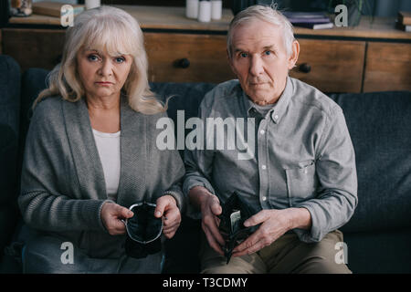 Senior couple sitting on couch, à la caméra et au porte-monnaie portefeuille Banque D'Images