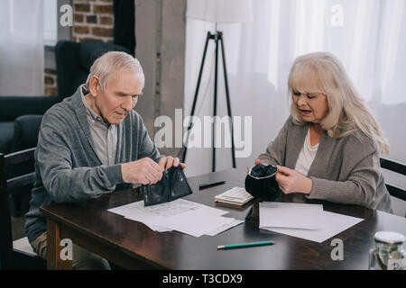 Senior couple holding portefeuille tout en étant assis à table avec les documents Banque D'Images