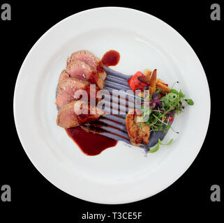 Filet de veau avec purée de violette, de ris de veau et légumes isolated on black Banque D'Images