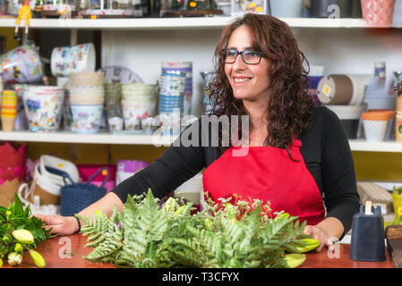 Portrait of woman wearing apron fleuriste debout à l'encontre de décisions bouquet pour client au magasin de fleur . Banque D'Images