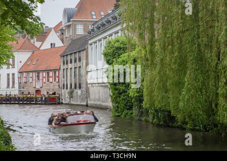 Bruges, Belgique - 17 mai 2012 : les vieilles maisons sur le canal d'eau, d'arbres et un bateau moteur flottant sur un jour de printemps. Banque D'Images
