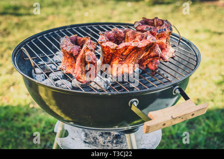 Côtes levées couronne rôti sur BBQ barbecue électrique grill. La couronne de porc fait maison côtes levées sur le gril à l'aide de faible et lente. La cuisson à l'extérieur dans une nature Banque D'Images