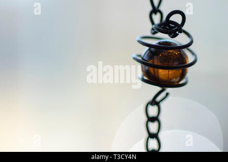 Coloreed Amber glass bead dans sprial metal avec fond neutre et copy space Banque D'Images