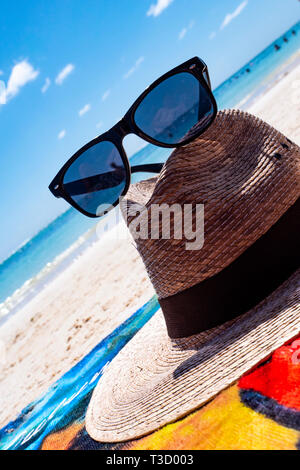 Chapeau de paille, sac, lunettes de soleil et tongs sur une plage tropicale Banque D'Images