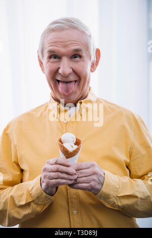 Man sticking tongue out, et la tenue de cornet de crème glacée à la maison Banque D'Images