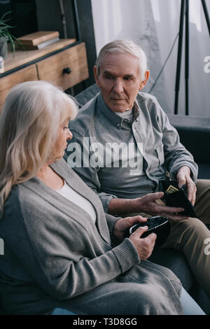 Senior couple sitting on couch et holding portefeuille à Accueil Banque D'Images