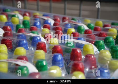 Tas de bouchons de bouteilles en plastique coloré dans la rangée. Banque D'Images