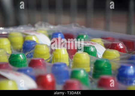 Tas de bouchons de bouteilles en plastique coloré dans la rangée. Banque D'Images