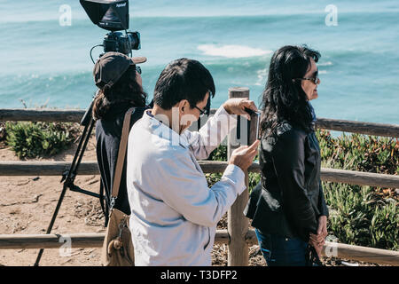 Le Portugal, Sintra, le 26 juin 2018 : les touristes asiatiques sur Cape Roca. L'un d'eux est de prendre des photos. Dans l'arrière-plan est l'océan Atlantique. Banque D'Images