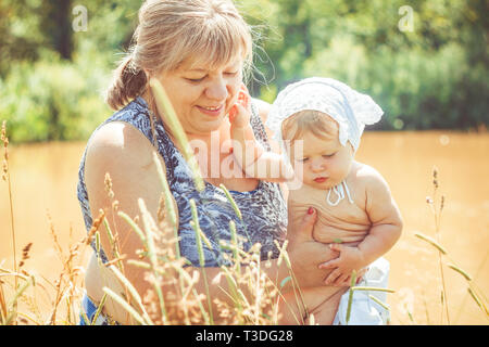 Grand-mère est titulaire d'une petite fille nouveau-né dans ses bras. Banque D'Images