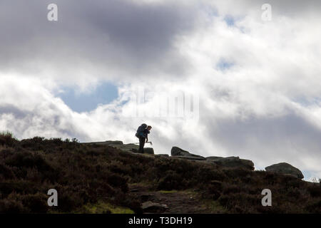 Un randonneur solitaire sur la crête à Bamford bord dans l'anglais Peak District, Derbyshire, UK avec un moody sky derrière lui Banque D'Images