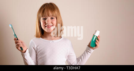 Smiling girl avec brosse à dents et dentifrice sur brown isolés. Composition horizontale. Banque D'Images