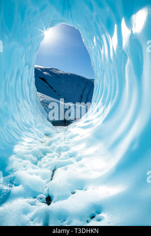 Dans l'Alaska Backountry sur le Glacier Matanuska, le soleil brille par l'ouverture d'une vaste caverne de glace. Le bleu profond de la caverne de glace cireur Banque D'Images
