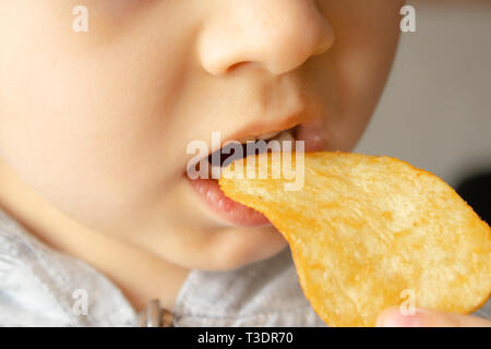 Baby eating chips. Close-up. L'enfant tient les jetons. La malbouffe. Banque D'Images