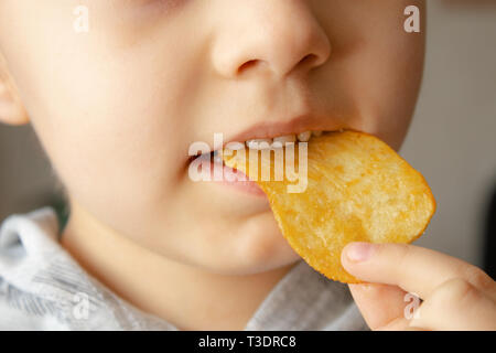 Baby eating chips. Close-up. L'enfant tient les jetons. La malbouffe. Banque D'Images