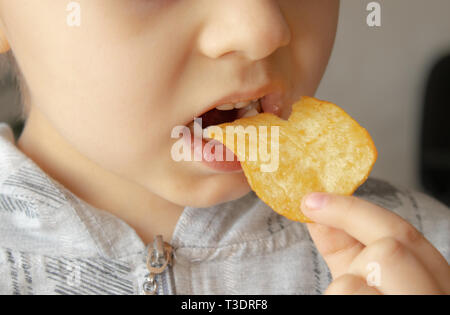 Baby eating chips. Close-up. L'enfant tient les jetons. La malbouffe. Banque D'Images