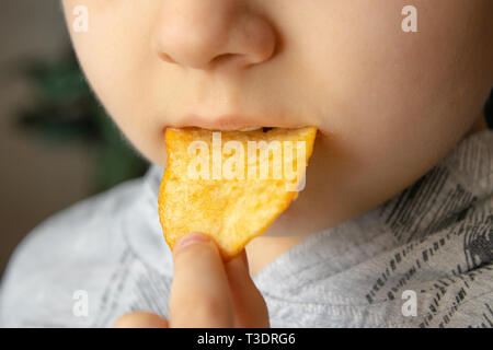 Baby eating chips. Close-up. L'enfant tient les jetons. La malbouffe. Banque D'Images