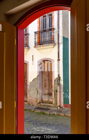 Vieille porte à l'architecture coloniale est détériorée par le temps vu à travers une autre porte aussi vieux et avec la même architecture dans la ville d'Ouro Preto Banque D'Images