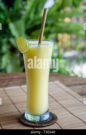 Le jus de mangue dans un grand verre avec paille de bambou, décoré avec de la chaux. Banque D'Images