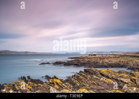 En regardant la Rocky Harbour à l'ancienne jetée à Portencross dans Seamill West Kilbride par une froide journée lumineuse en Ecosse. L'image est une longue exposition à Banque D'Images