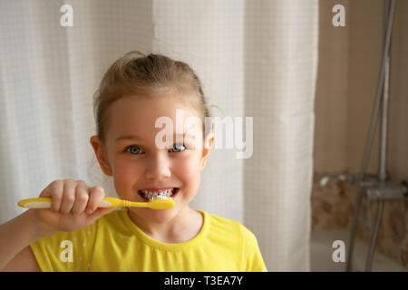 Peu cute blonde girl brosse les dents avec une brosse à dents dans la salle de bains, procédure matin Banque D'Images