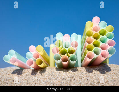 Des piles de pailles en plastique coloré sur le sable contre le ciel bleu, selective focus. Banque D'Images