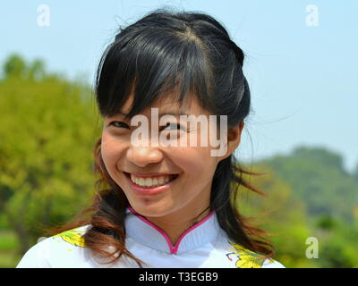 Charmante fille vietnamienne avec les cheveux bouclés blanc porte une robe de soie traditionnel vietnamien áo dài (sourires) et pour l'appareil photo. Banque D'Images