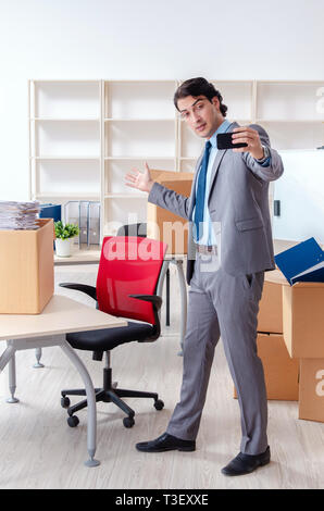 Jeune homme employé avec des cases dans le bureau Banque D'Images