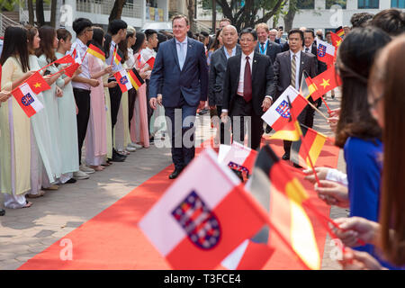 09 avril 2019, Hanoi, Vietnam : Bodo Ramelow (l, à gauche), premier ministre de la Thuringe, et Recteur Pham Duy Hoa, Université nationale de Génie Civil (in nuce) Hanoi, marcher sur le tapis rouge en face de la délégation de Thuringe à travers un treillis d'étudiants brandissant des drapeaux pour signer un contrat d'intensifier la coopération entre l'Université de Hanoi et Nordhausen Université de Sciences Appliquées. Sur le voyage de sept jours, environ 100 représentants du monde des affaires, la science et la politique se rendra à Hanoi et Ho Chi Minh Ville (Saigon), avec l'accent sur le recrutement de travailleurs qualifiés pour les entreprises de Thuringe. Photo : Banque D'Images