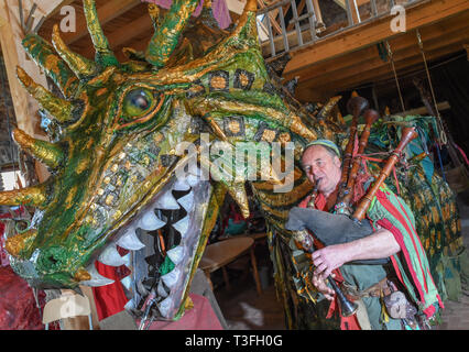 Golzow, Allemagne. Le 08 Avr, 2019. Streisand romain, musicien et artiste, joue sur une cornemuse à côté d'un grand dragon figure dans une grange de sa Kulturhof. Le monastère de Pâques Festival en avant du fond de monastère de Chorin est devenu une institution et pour de nombreuses familles une excursion doit les jours fériés. Cette année, il y a la 30e édition. Il a été inventé par Roman Streisand, qui tire toujours les cordes avec son pilwut "bande médiéval'. Crédit : Patrick Pleul/dpa-Zentralbild/ZB/dpa/Alamy Live News Banque D'Images