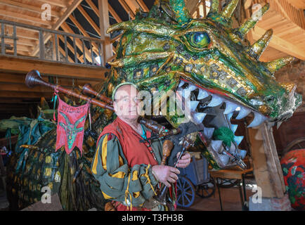 Golzow, Allemagne. Le 08 Avr, 2019. Streisand romain, musicien et artiste, se dresse avec une cornemuse à côté d'un grand dragon figure dans une grange de sa Kulturhof. Le monastère de Pâques Festival en avant du fond de monastère de Chorin est devenu une institution et pour de nombreuses familles une excursion doit les jours fériés. Cette année, il y a la 30e édition. Il a été inventé par Roman Streisand, qui tire toujours les cordes avec son pilwut "bande médiéval'. Crédit : Patrick Pleul/dpa-Zentralbild/ZB/dpa/Alamy Live News Banque D'Images