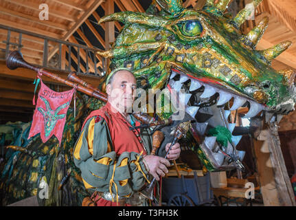 Golzow, Allemagne. Le 08 Avr, 2019. Streisand romain, musicien et artiste, se dresse avec une cornemuse à côté d'un grand dragon figure dans une grange de sa Kulturhof. Le monastère de Pâques Festival en avant du fond de monastère de Chorin est devenu une institution et pour de nombreuses familles une excursion doit les jours fériés. Cette année, il y a la 30e édition. Il a été inventé par Roman Streisand, qui tire toujours les cordes avec son pilwut "bande médiéval'. Crédit : Patrick Pleul/dpa-Zentralbild/ZB/dpa/Alamy Live News Banque D'Images