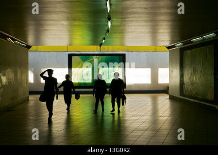 Un groupe de quatre piétons, reconnaissables comme des silhouettes, marcher dans un tunnel souterrain à Manille, Philippines Banque D'Images